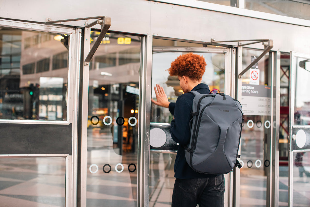 A man carrying a travel backpack heading inside an airport